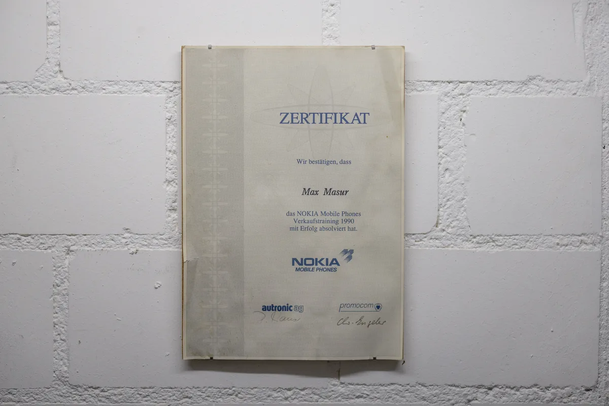 Ein Verkaufstrainingszertifikat der Marke Nokia von 1990 hängt an der Wand.
